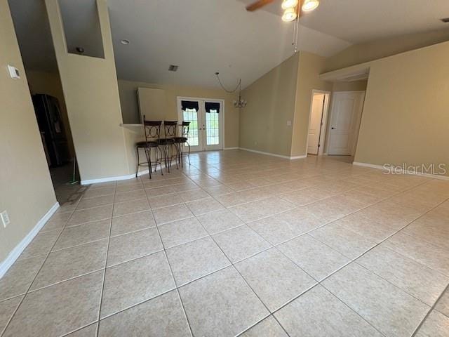 interior space featuring baseboards, ceiling fan, tile patterned flooring, vaulted ceiling, and french doors