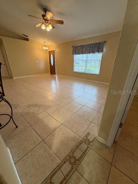 empty room with light tile patterned flooring, a ceiling fan, and baseboards