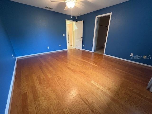 unfurnished bedroom with baseboards, visible vents, ceiling fan, and wood finished floors