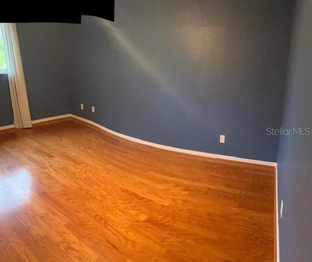 empty room featuring baseboards and wood finished floors