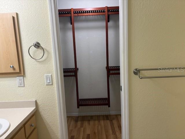 bathroom with a textured wall, vanity, and wood finished floors