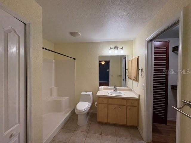 full bathroom featuring a shower, toilet, tile patterned flooring, a textured ceiling, and vanity