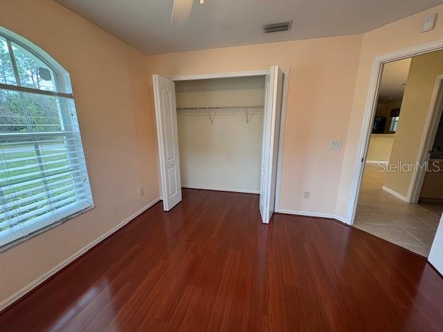 unfurnished bedroom featuring a closet, multiple windows, baseboards, and wood finished floors