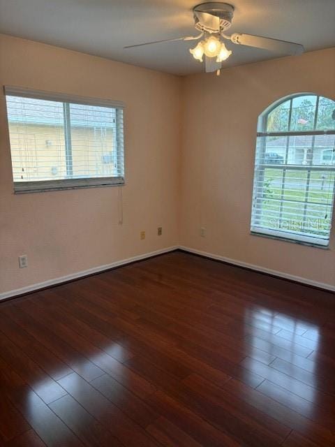 empty room featuring a ceiling fan, baseboards, and hardwood / wood-style flooring