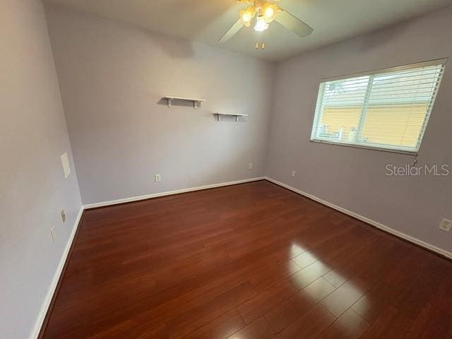 unfurnished room with a ceiling fan, dark wood finished floors, and baseboards