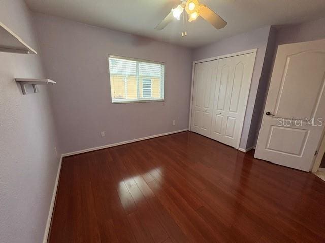 unfurnished bedroom featuring a ceiling fan, a closet, baseboards, and wood finished floors