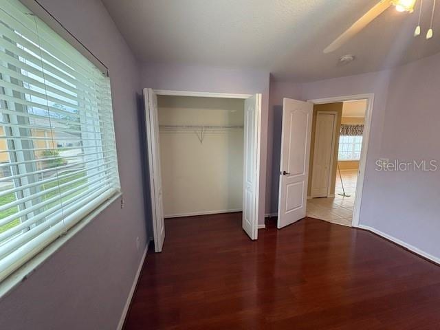 unfurnished bedroom featuring a closet, baseboards, and wood finished floors