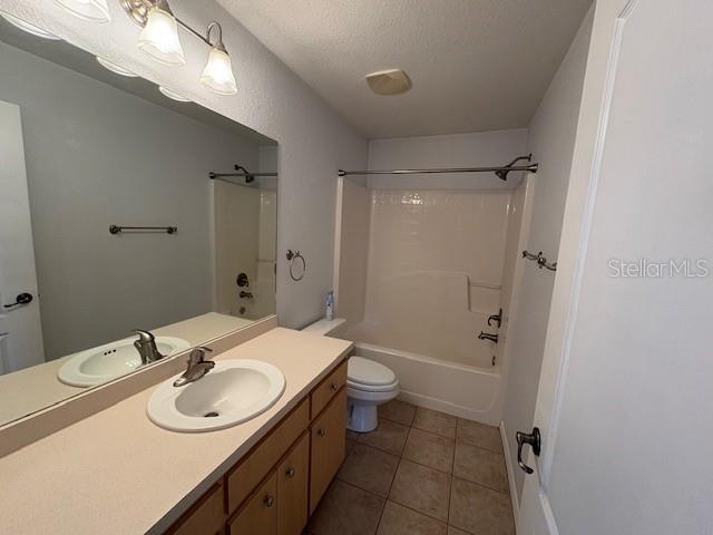 bathroom with toilet, tub / shower combination, vanity, a textured ceiling, and tile patterned floors