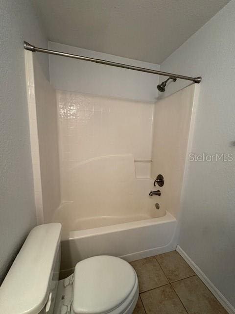 bathroom featuring baseboards, bathtub / shower combination, toilet, and tile patterned floors