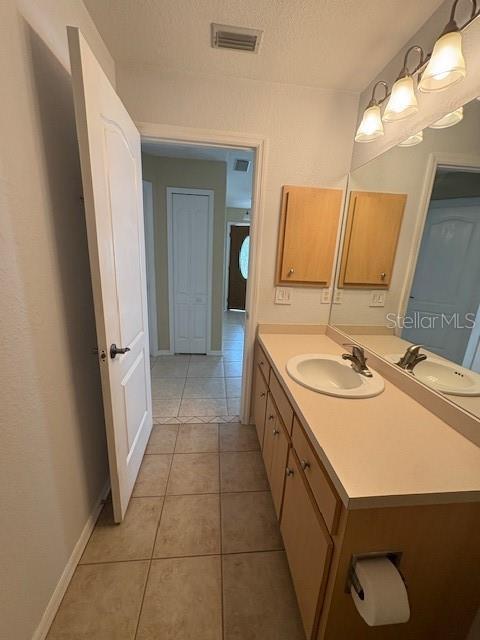 bathroom with visible vents, a textured ceiling, vanity, tile patterned flooring, and baseboards