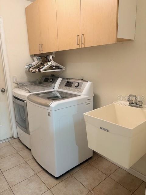 washroom featuring light tile patterned floors, independent washer and dryer, a sink, and cabinet space