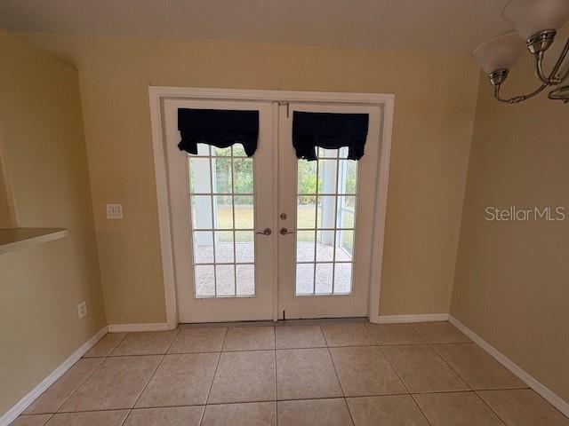 doorway to outside featuring french doors, baseboards, and light tile patterned floors