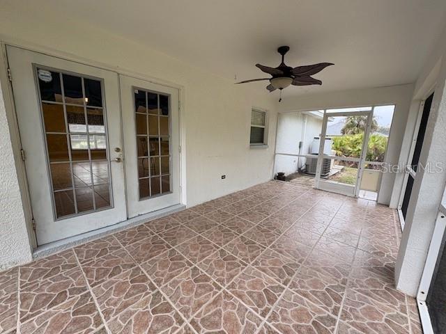 unfurnished sunroom with a ceiling fan and french doors