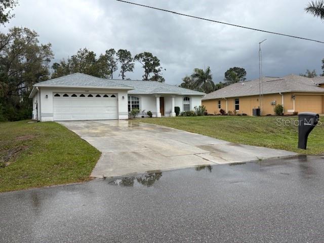 ranch-style home featuring concrete driveway, a front lawn, and an attached garage