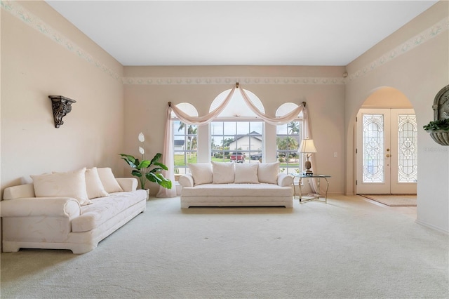 carpeted living room with french doors and baseboards