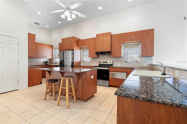 kitchen featuring appliances with stainless steel finishes, brown cabinets, a sink, and light tile patterned flooring