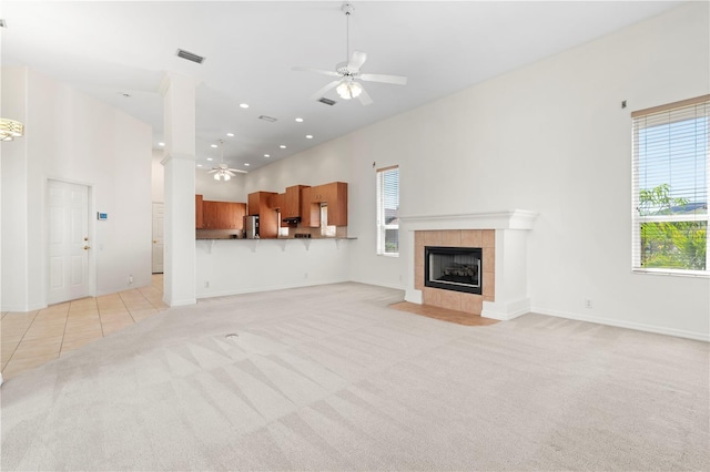 unfurnished living room featuring light colored carpet, ceiling fan, visible vents, and a towering ceiling