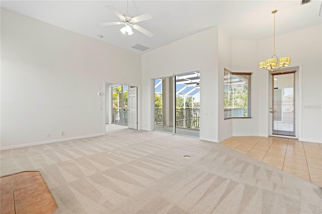 unfurnished living room with a towering ceiling, carpet flooring, a ceiling fan, and tile patterned floors