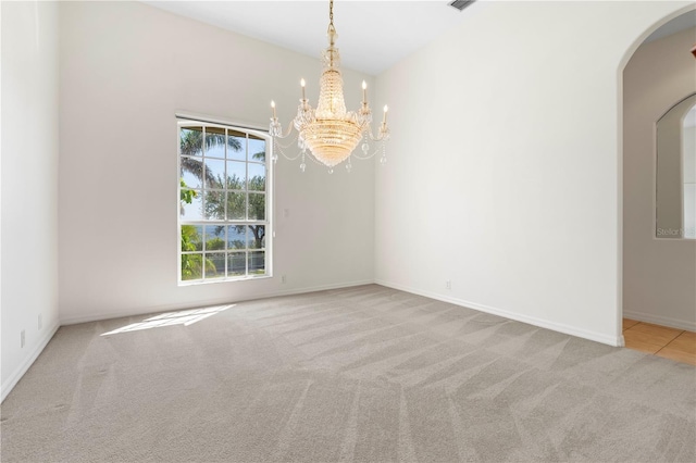 carpeted spare room with arched walkways, a notable chandelier, and baseboards