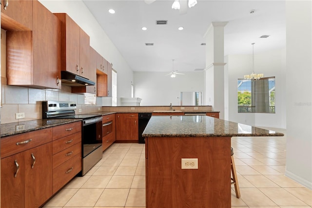 kitchen featuring light tile patterned flooring, stainless steel range with electric cooktop, a sink, under cabinet range hood, and ceiling fan with notable chandelier