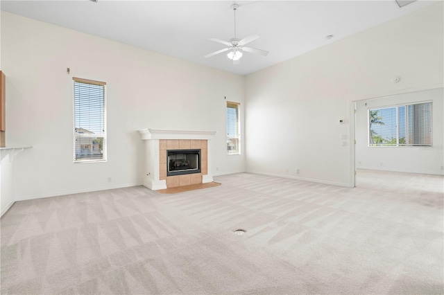 unfurnished living room featuring a fireplace, baseboards, a ceiling fan, and light colored carpet