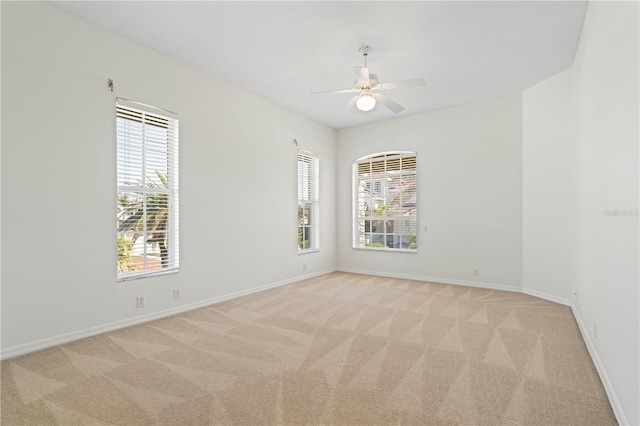 spare room with light carpet, ceiling fan, and baseboards