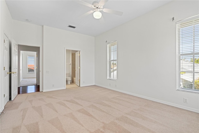 unfurnished bedroom featuring light colored carpet, visible vents, baseboards, and multiple windows