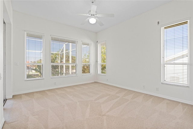 spare room featuring light carpet, baseboards, and a ceiling fan