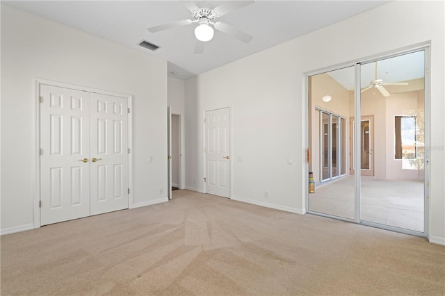 unfurnished bedroom featuring light carpet, visible vents, and multiple closets