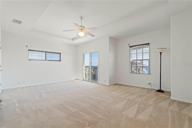 unfurnished room with baseboards, a raised ceiling, visible vents, and light colored carpet