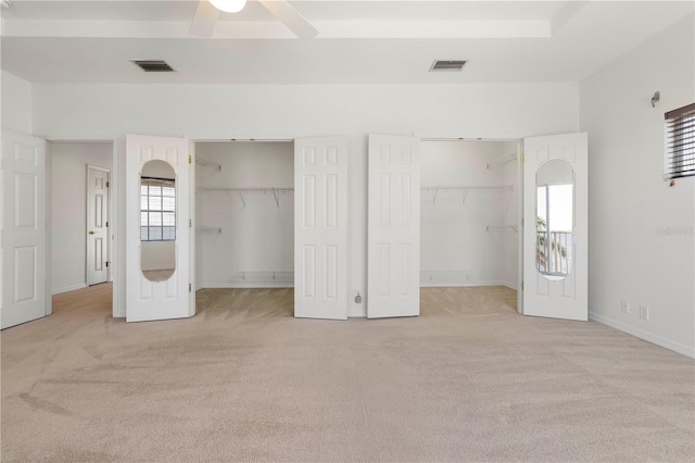 unfurnished bedroom with carpet floors, visible vents, and multiple closets