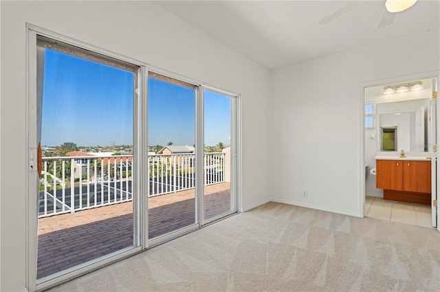 interior space featuring light colored carpet, a ceiling fan, baseboards, access to outside, and ensuite bath