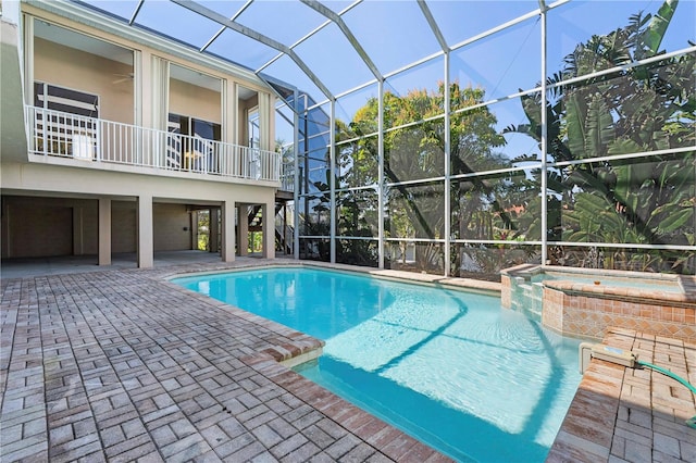 view of pool with glass enclosure, a patio area, and a pool with connected hot tub