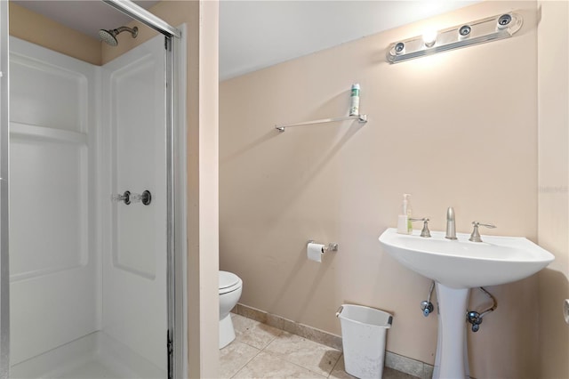 full bath featuring toilet, a sink, baseboards, tile patterned floors, and a stall shower