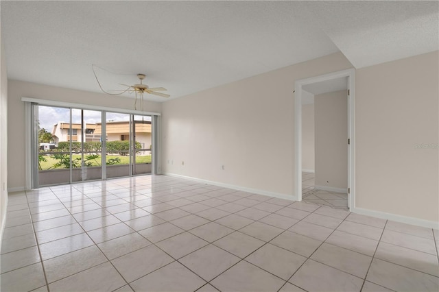 spare room featuring ceiling fan, baseboards, and light tile patterned flooring