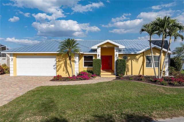 ranch-style house featuring stucco siding, metal roof, an attached garage, decorative driveway, and a front yard