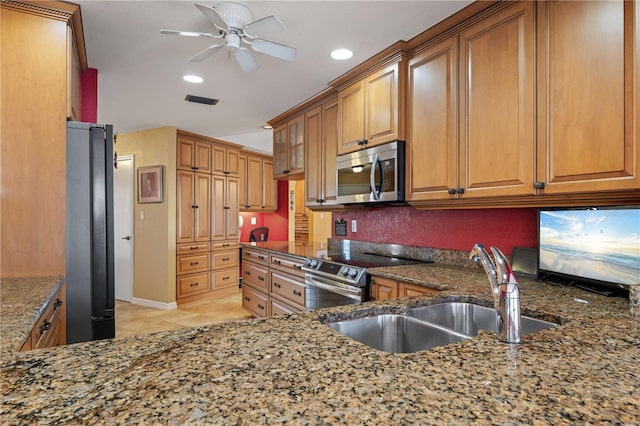 kitchen with stainless steel appliances, stone countertops, brown cabinetry, and a sink