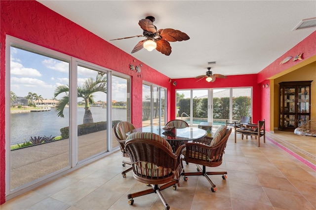 sunroom / solarium with plenty of natural light, visible vents, and a water view