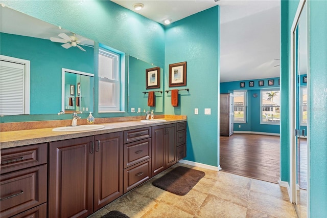 full bath featuring a ceiling fan, a sink, baseboards, and double vanity