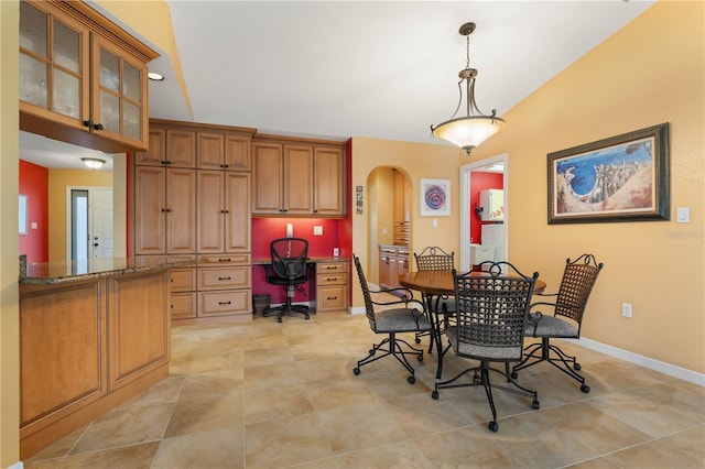 dining space with arched walkways, built in desk, baseboards, and light tile patterned floors