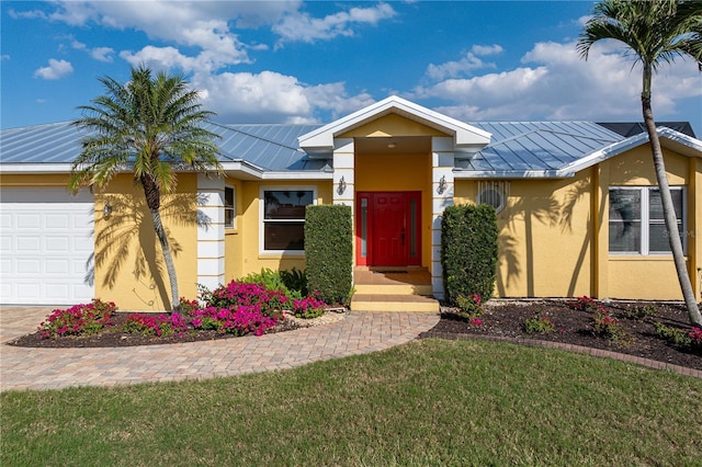 single story home with metal roof, a garage, stucco siding, a front lawn, and a standing seam roof