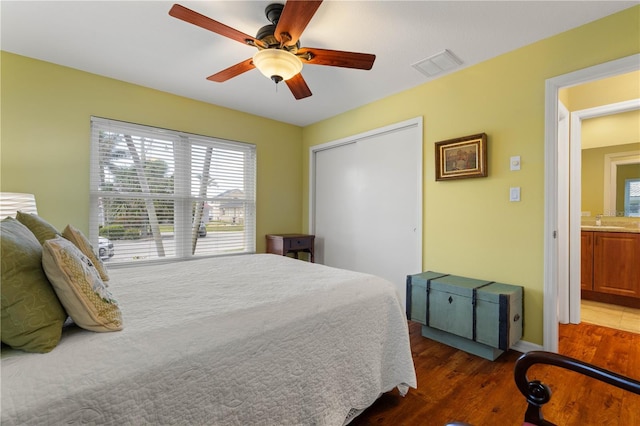 bedroom with ceiling fan, a sink, wood finished floors, visible vents, and a closet