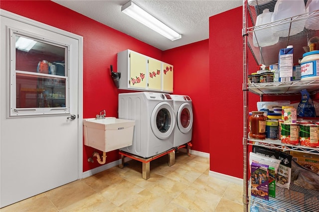 laundry room with a textured ceiling, laundry area, separate washer and dryer, a sink, and baseboards