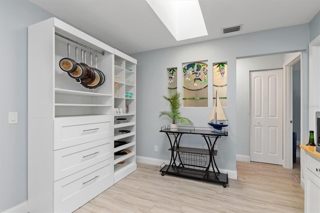 walk in closet with a skylight, wood tiled floor, and visible vents