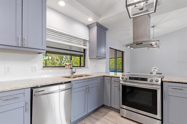 kitchen featuring light stone countertops, gray cabinetry, stainless steel appliances, a sink, and decorative backsplash