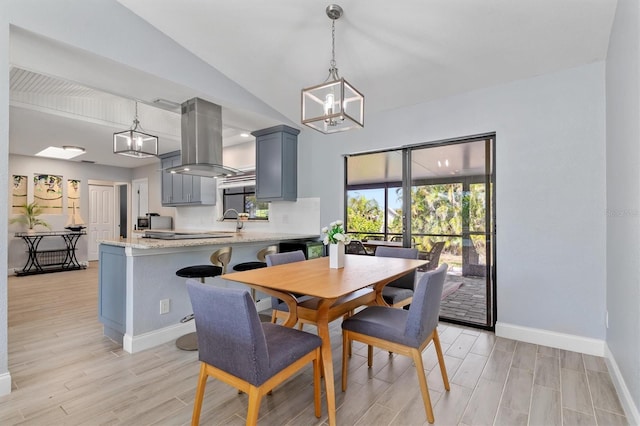 dining space with lofted ceiling, a notable chandelier, light wood-style flooring, and baseboards