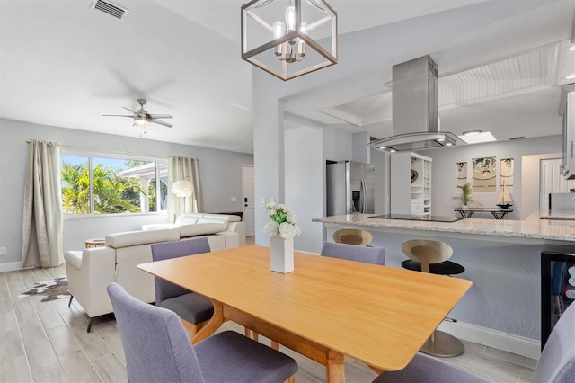 dining area featuring baseboards, ceiling fan with notable chandelier, visible vents, and wood tiled floor