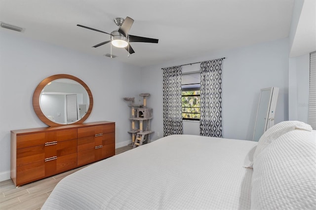 bedroom with baseboards, ceiling fan, visible vents, and wood tiled floor