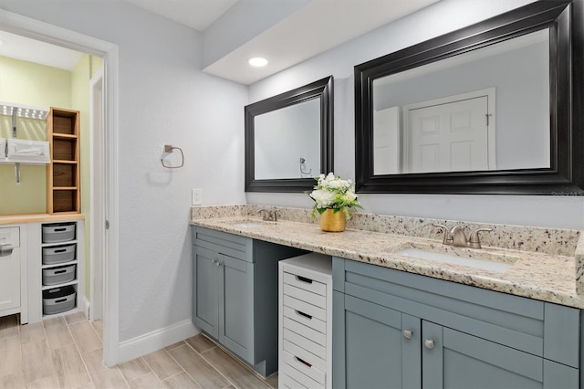 bathroom featuring a sink, baseboards, and double vanity