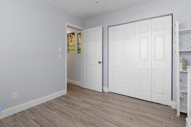 unfurnished bedroom with baseboards, a closet, and wood finish floors